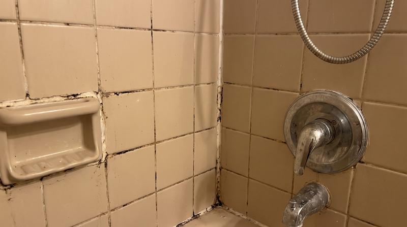 Cracked caulk and stained grout before repair