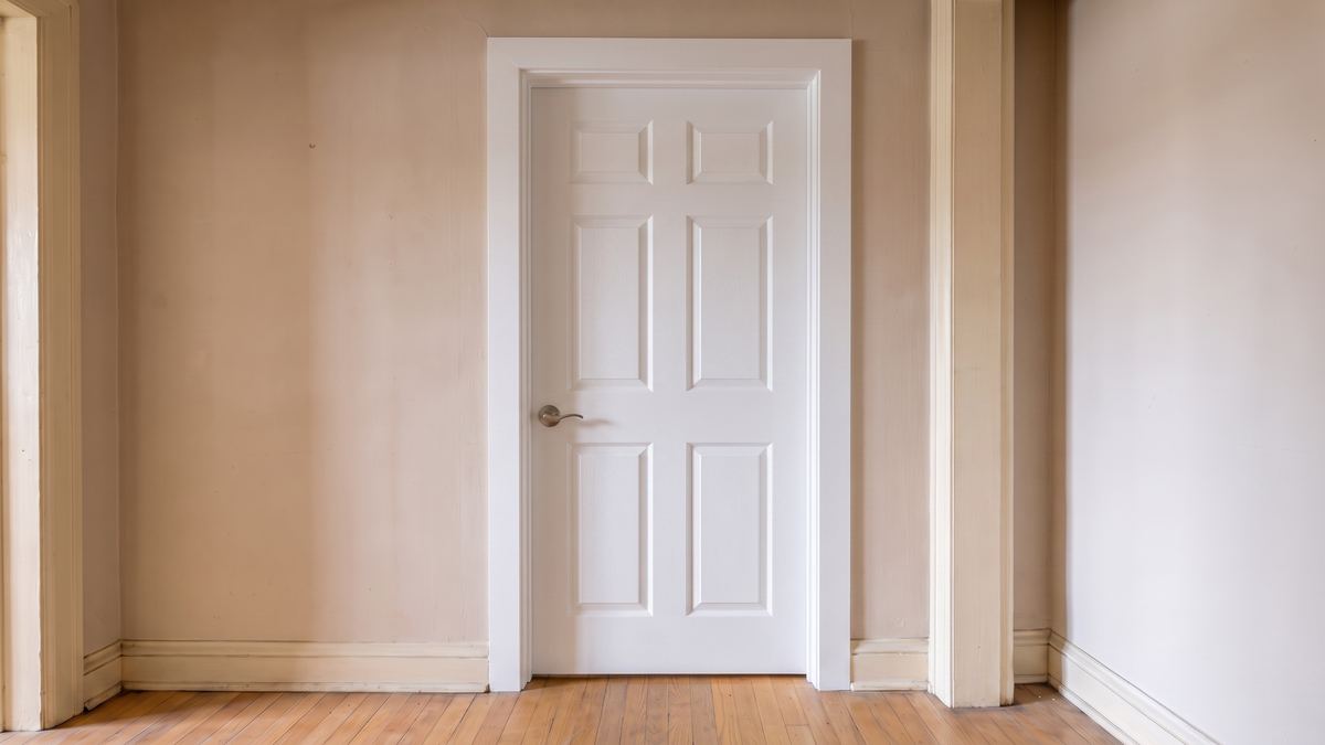The same doorway with a new prehung six-panel door, new jamb, new casing and a new lever, the rest of the hallway untouched