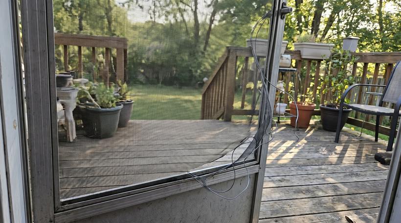 Patio screen door with the mesh ripped out of the frame and hanging loose