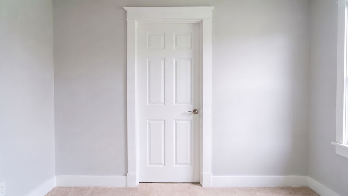 A new primed six-panel slab door with a new lever hung in the same frame and casing