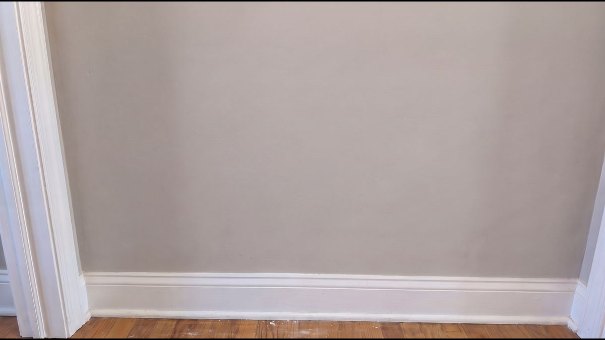 The same wall with the hole patched, textured and primed, invisible