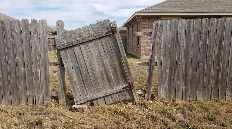 Damaged leaning wood fence before repair