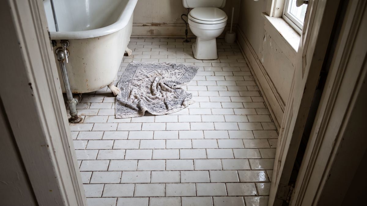 Bathroom with glossy slippery tile and a loose rug