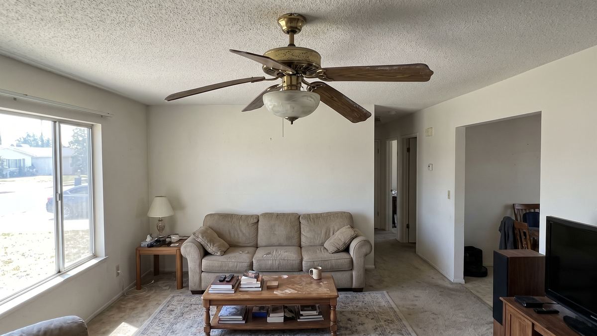 Living room with an old brass ceiling fan with worn blades