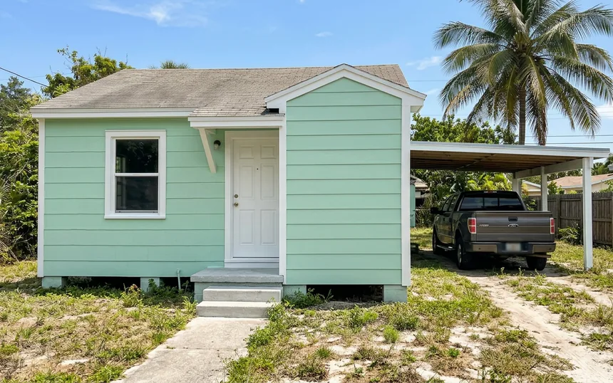 After: the same cottage with new lap siding and corner board, painted mint green with white trim