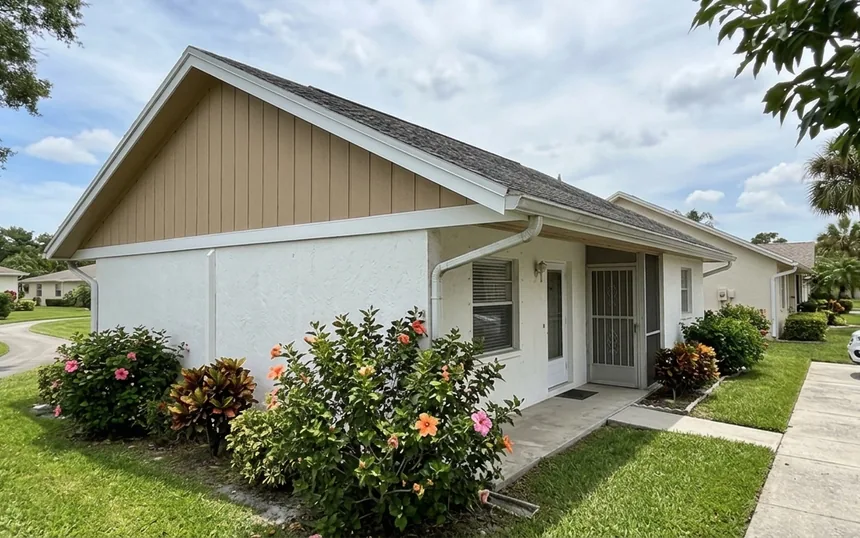 After: the same villa with new panel siding on the gable and a new fascia board, painted tan and white