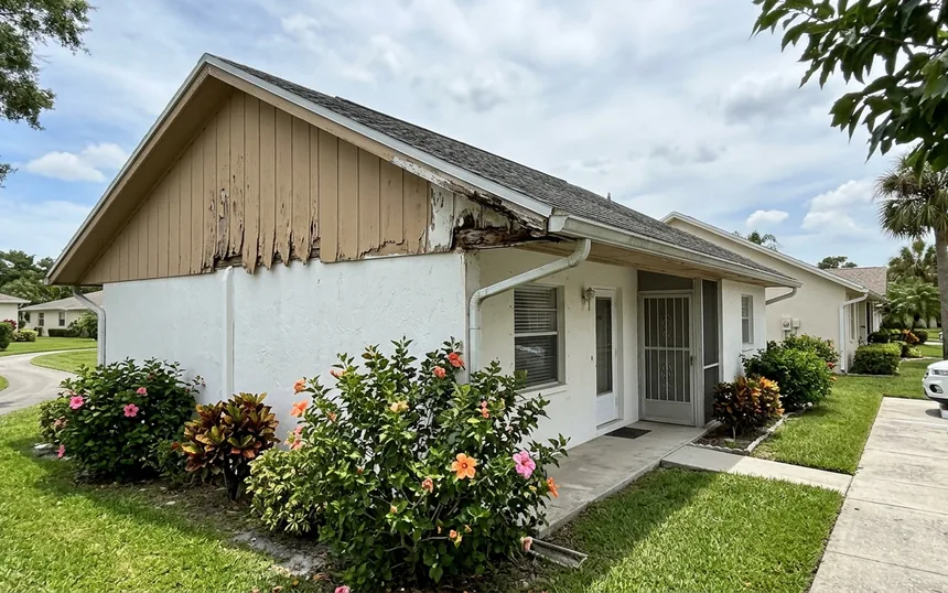 Before: delaminating, rotted plywood panel siding on the gable of a 1970s stucco villa, with soft fascia