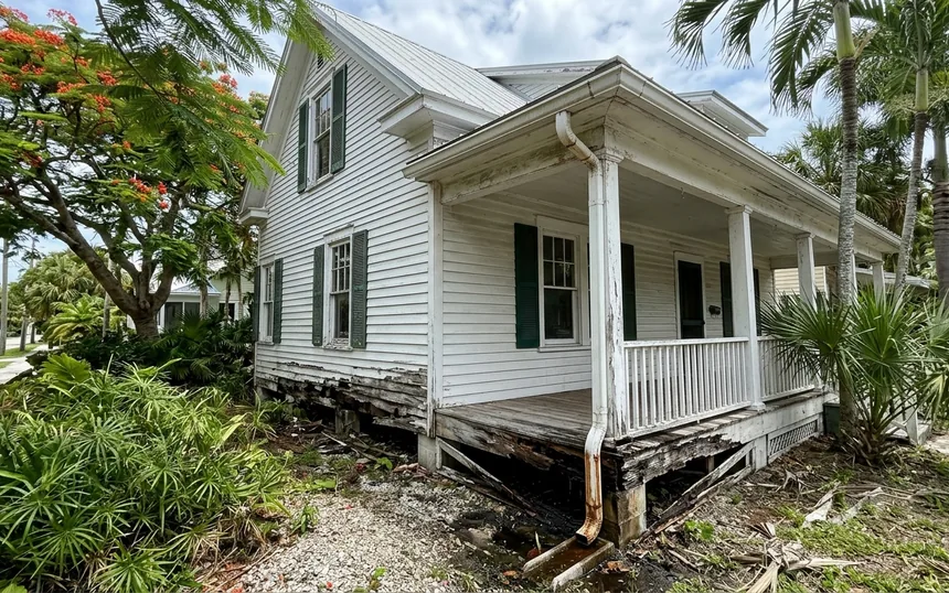 Before: rotted, split lap siding and porch skirt boards on a white two-story 1920s wood frame house