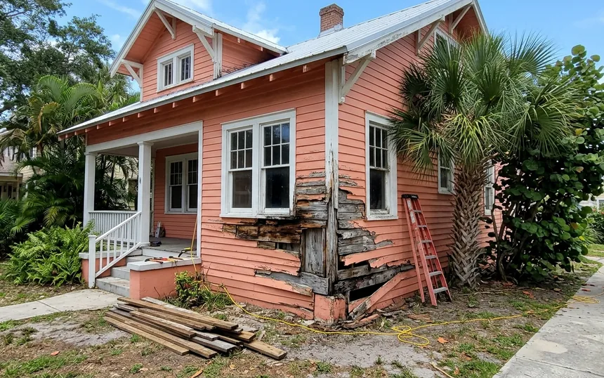 Before: rotted, split lap siding at the front corner of a coral 1920s wood frame house