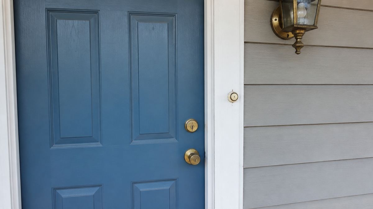 Front door with an old wired doorbell button and keyed deadbolt