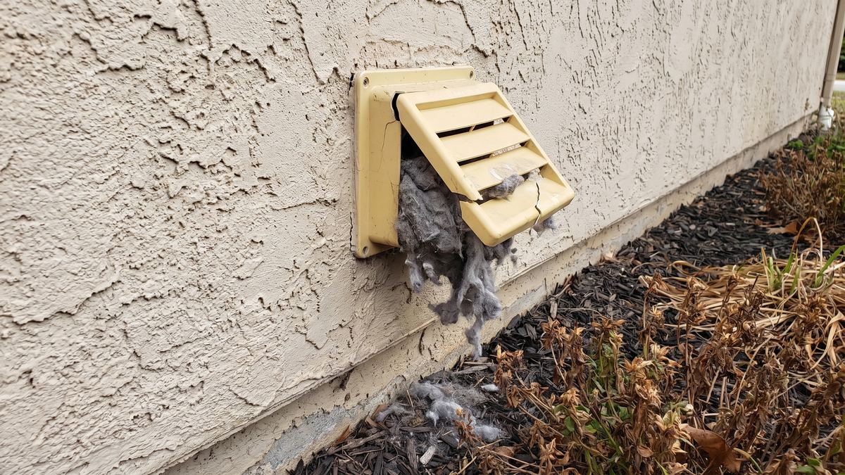 Outside dryer vent hood clogged with lint and a broken flap