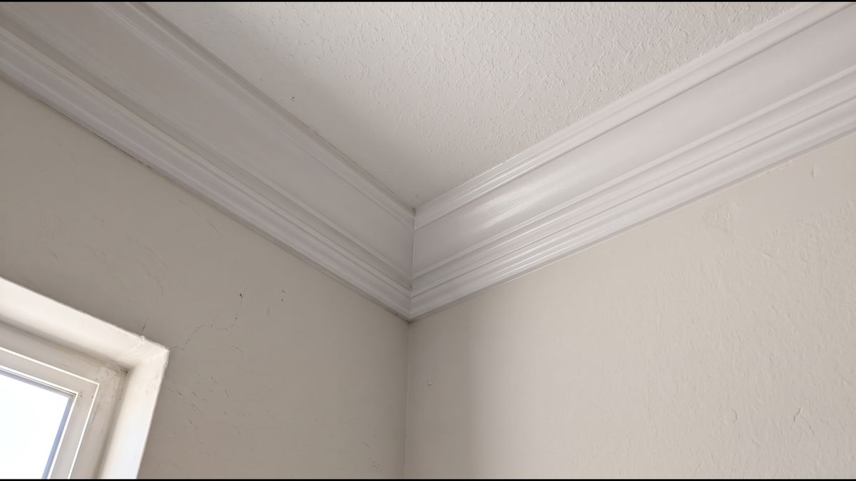The same crown molding repaired, inside corner closed tight, nails set and filled, caulked and painted white