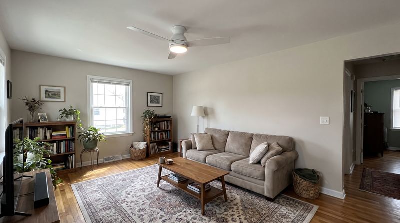 A white ceiling fan with an LED light installed in a living room