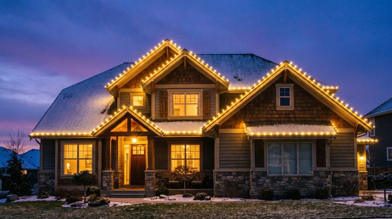 Warm white holiday lights installed along a roofline at dusk