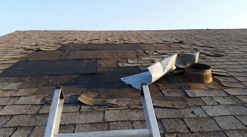 A shingle roof with missing shingles and bent flashing before repair
