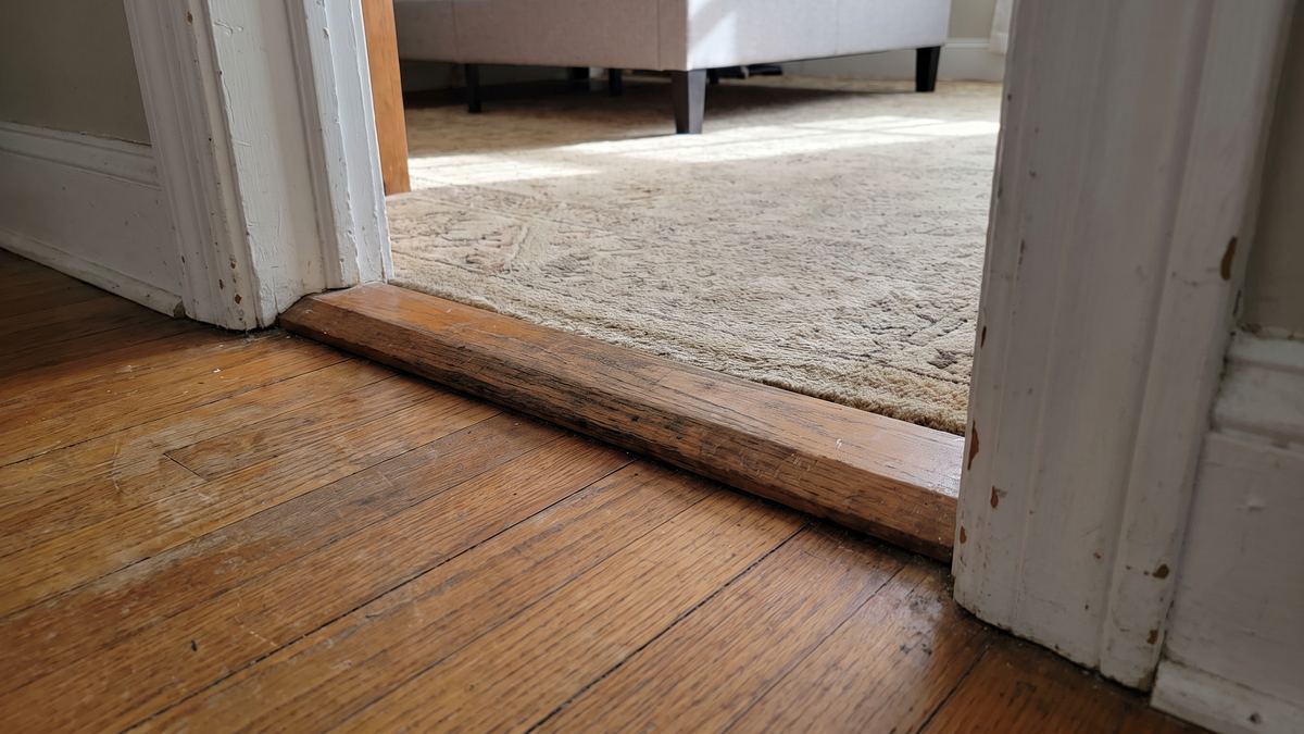 Tall raised wooden threshold in a doorway, a trip hazard