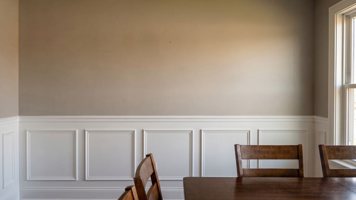 Dining room wall with white picture-frame wainscoting and chair rail installed