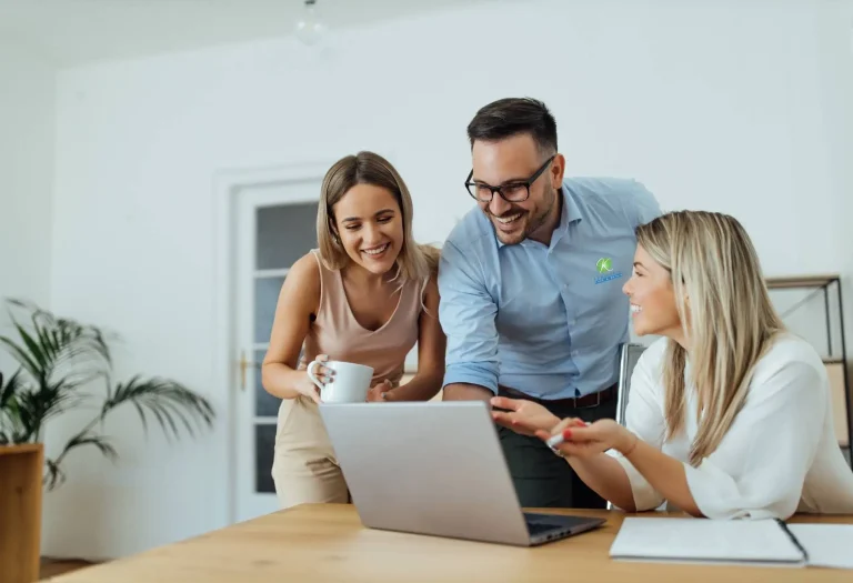 Three franchise team members reviewing plans together on a laptop in a bright office