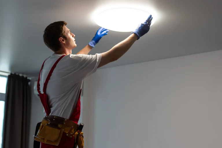 Technician installing a round LED ceiling light fixture in a home