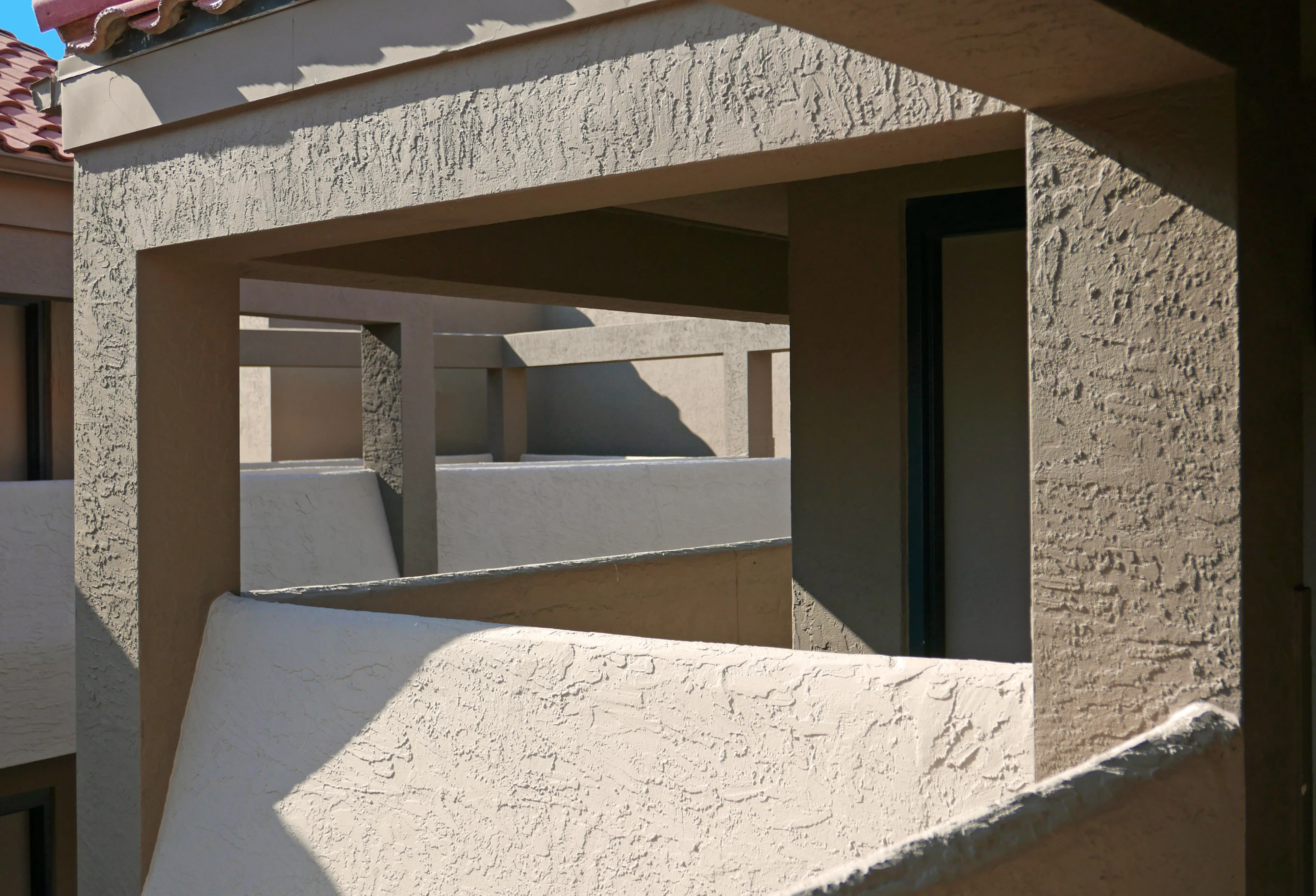 Architectural stucco detail on the breezeways of a modern building — before and after comparison
