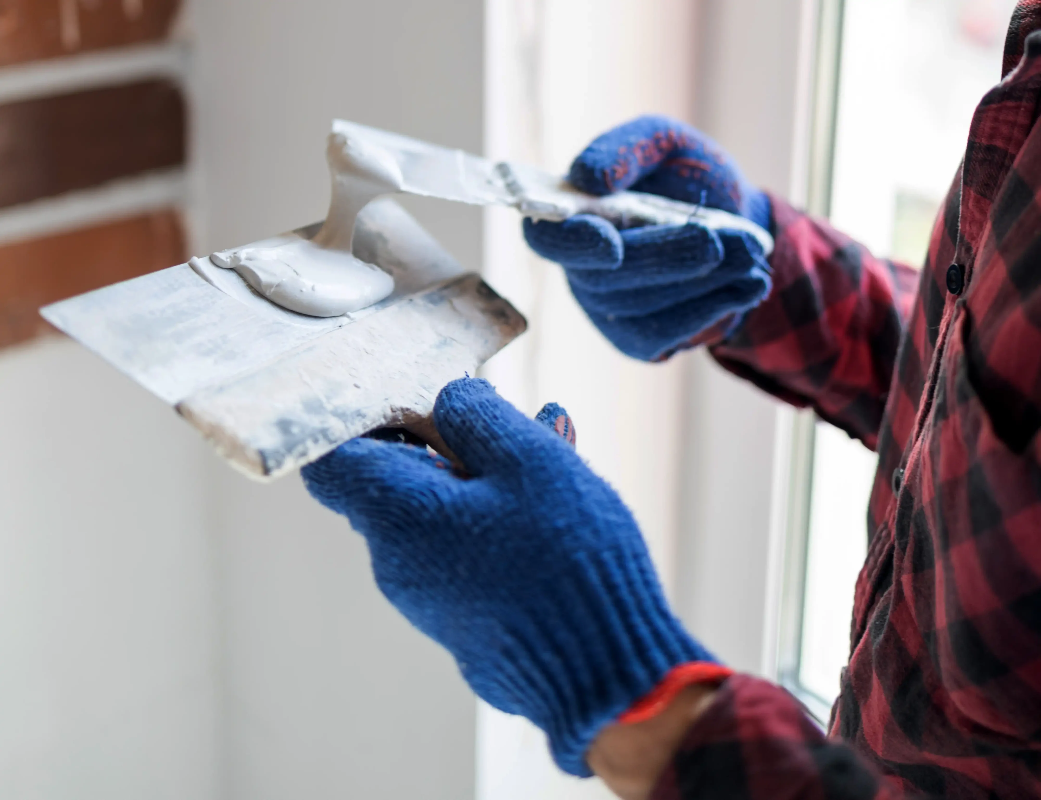 Hands applying putty on wall to patch drywall holes — professional finish