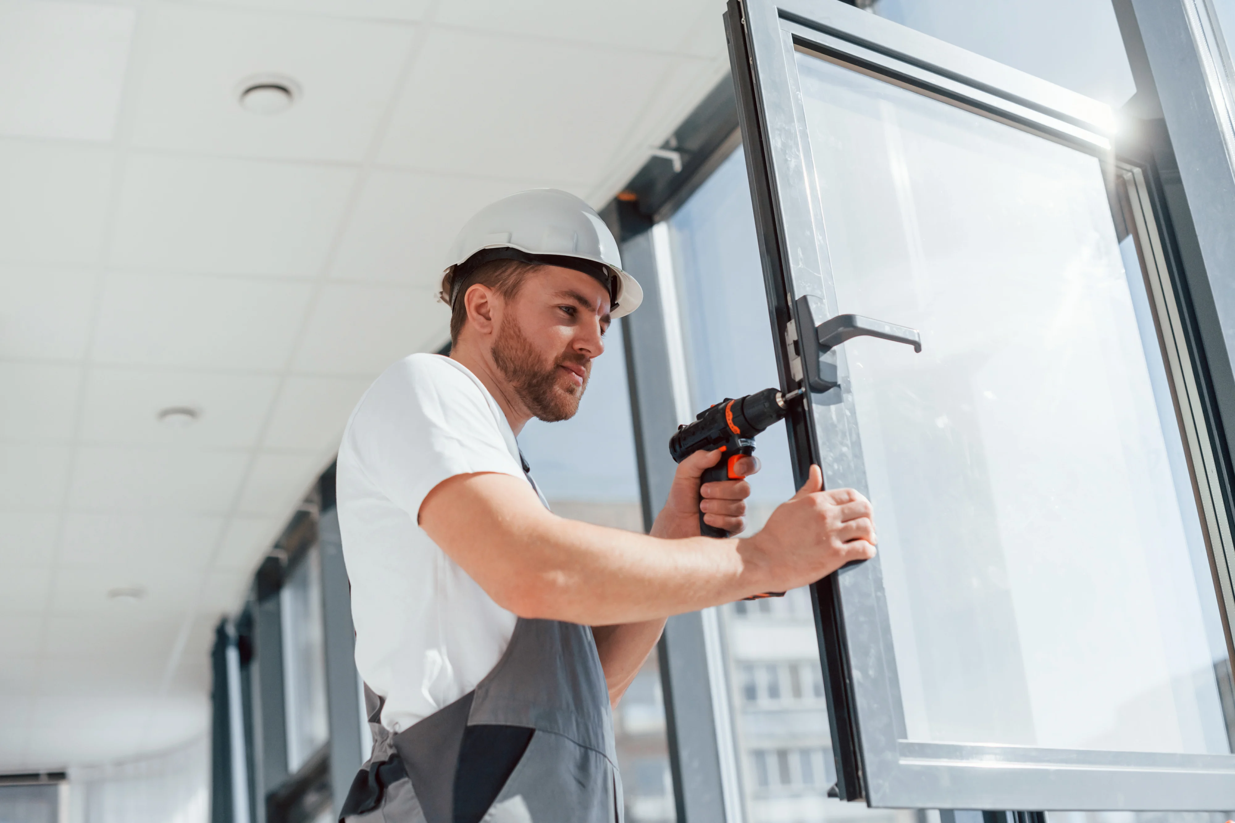 Construction worker installing a large glass panel in a modern home