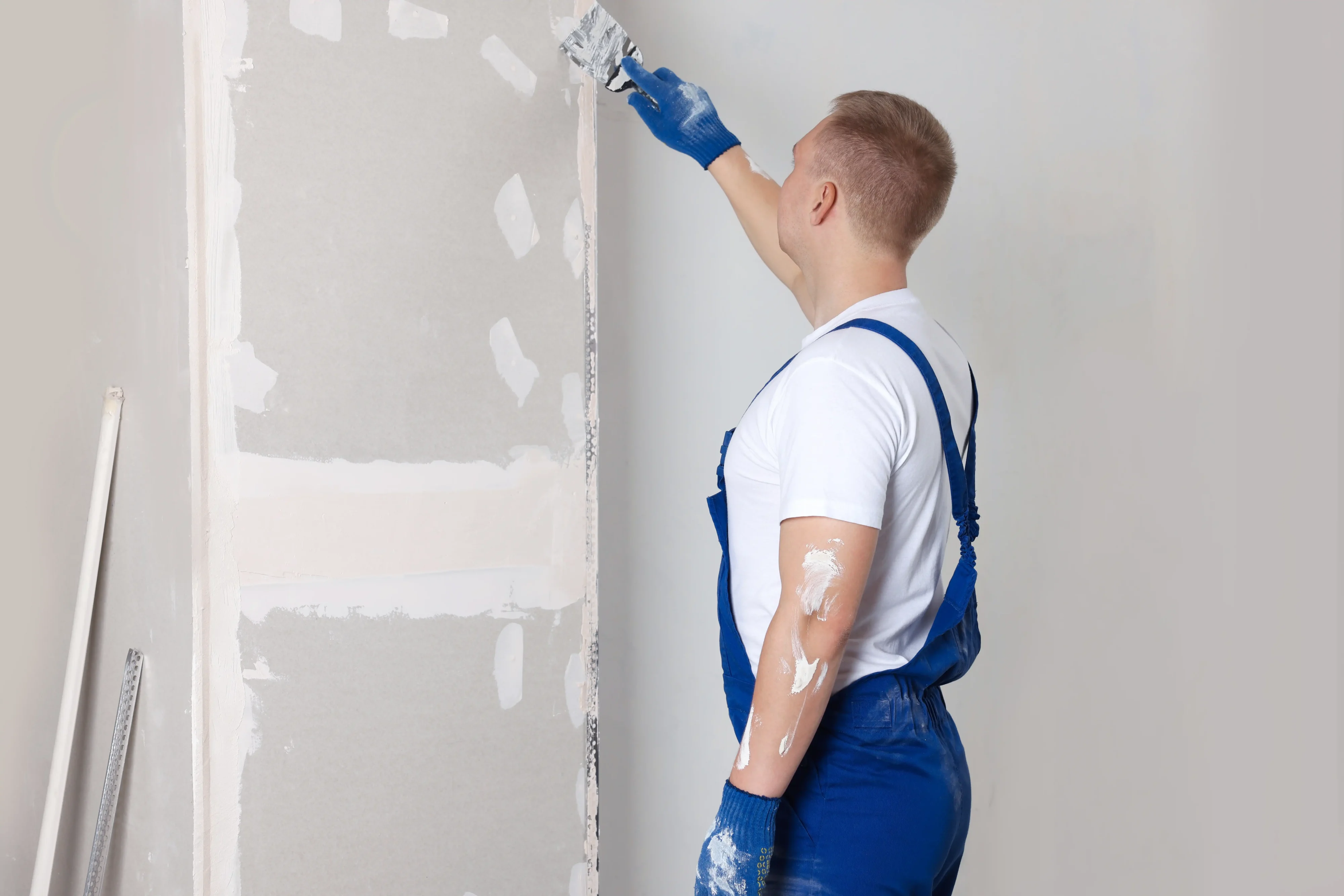 Drywall worker applying mesh tape with putty knife for seamless wall repair