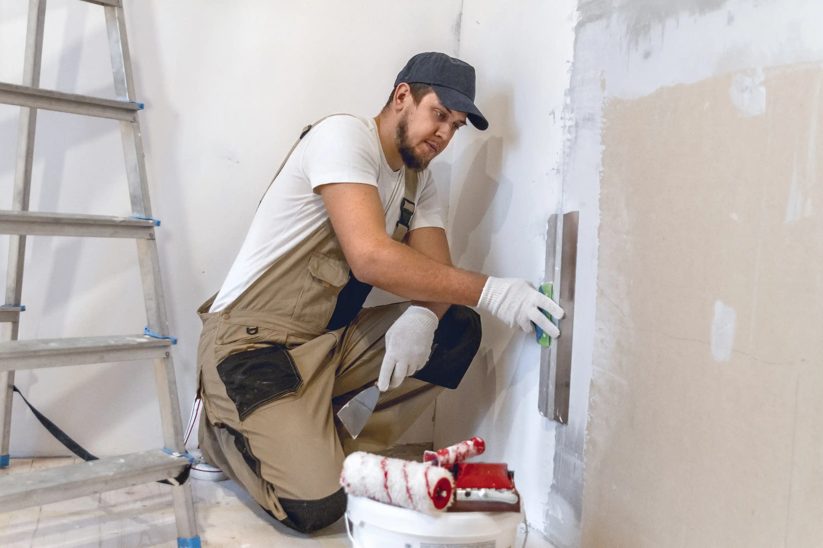 Worker applying drywall compound to residential wall for paint-ready finish