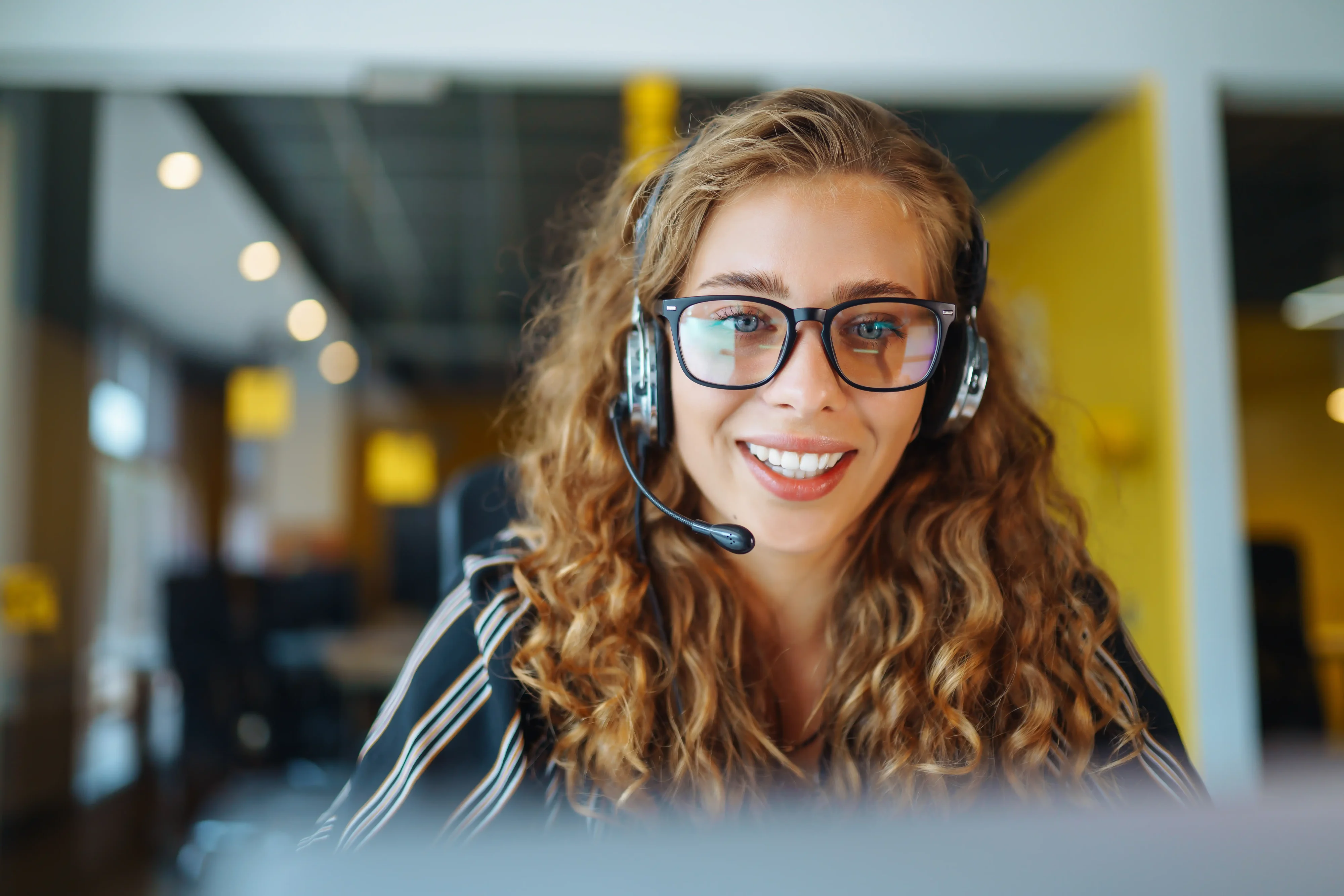 Friendly young female agent in a call centre ready to take your call